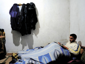 Durante el invierno, Shaman Alwawi, de 24 años, estudia bajo las mantas para protegerse del frío en casa. No tienen fuel suficiente para calentarse.