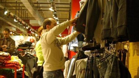 Imagen del interior de un establecimiento textil. En primer plano, un joven mira unas prendas de vestir.	 DN