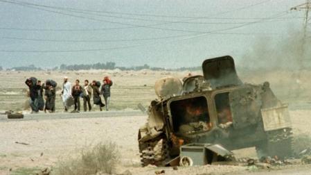 Un grupo de refugiados kuwaities pasa junto a un blindado destrozado en la carretera de Basora, días después del final de la Guerra del Golfo de 1991. 	REUTERS