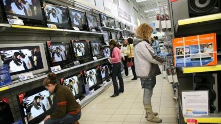 Varios clientes viendo televisiones y aparatos para poder ver la TDT, en un centro comercial. 	ARCHIVO