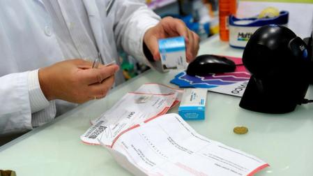 Un farmac&eacute;utico, dispensando medicamentos a un pensionista, este domingo