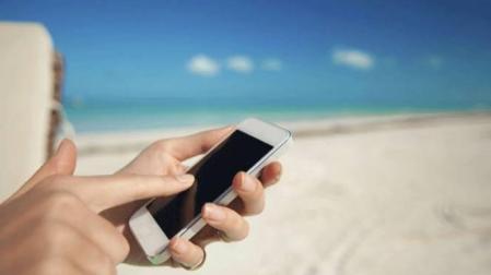 Una mujer usa el smartphone en la playa.