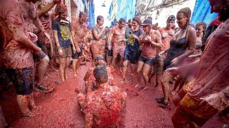 Varios jóvenes, durante la Tomatina en la calle principal de la localidad valenciana de Buñol que celebra el 70 aniversario de su tradicional fiesta, en la que participan más de 22.000 personas de 96 nacionalidades diferentes y en la que se lanzarán 150 toneladas de tomate, una cifra récord