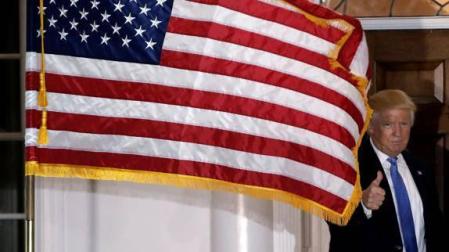 Donald Trump posa tras una bandera de Estados Unidos.
