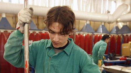 Un joven realiza un trabajo en una fábrica.