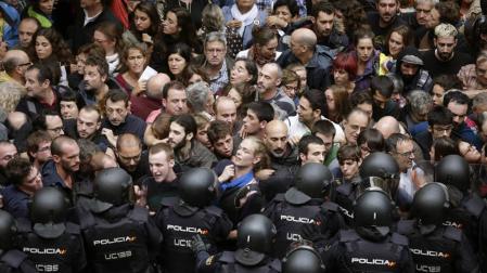Agentes antidisturbios de la Policía Nacional forman un cordón de seguridad en los alrededores del colegio Ramón Llull de Barcelona. Policía Nacional y Guardia Civil han desplegado a sus agentes en varios colegios electorales de Barcelona para impedir el referéndum del 1-O, suspendido por el Tribunal Constitucional (TC), lo que ha originado momentos de tensión y algún forcejeo con las personas concentradas ante los locales.
