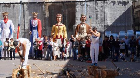 Dos aizkolaris, durante la exhibición de deporte rural y con los gigantes al fondo.