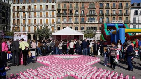 Una gran lazo rosa elaborado con cajas de leche junto a la carpa informativa.
