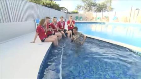 Entrevista a unos nadadores, tropieza y se sumerge en la piscina