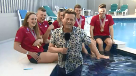 Entrevista a unos nadadores, tropieza y se sumerge en la piscina