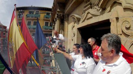 La vicepresidenta de la DYA, María Calado, y una de sus voluntarias más veteranas, Paula Ramirez, junto al alcalde de Pamplona, Joseba Asiron (d), prenden desde el balcón del Ayuntamiento la mecha del Chupinazo.