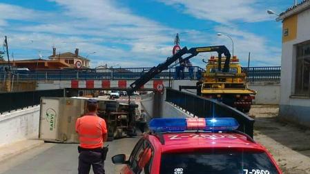 El conductor de un camión no respeta el límite de altura de un puente y vuelca en Caparroso