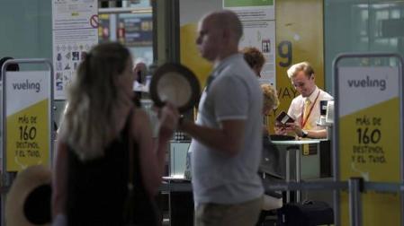 Personal de facturación de Vueling atiende a los viajeros en el Aeropuerto de El Prat.