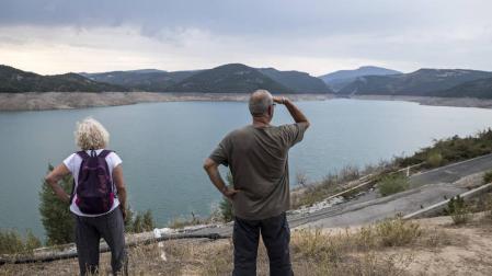 Dos personas contemplan  el bajo nivel del embalse de Itoiz, al 34% de su capacidad máxima.