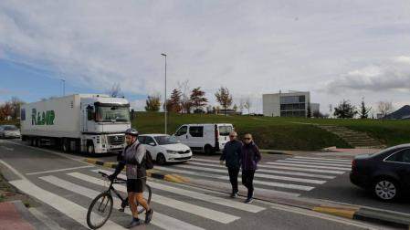 Un ciclista con la bici en la mano y dos peatones más cruzan por el paso de la carretera NA-2300 entre la rotonda de Sarriguren y el polígono Areta para llegar desde la Ciudad de la Innovación a Erripagaña.