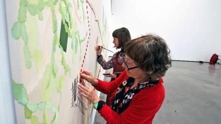 Teresa Sabaté (en primer plano), cosiendo en amarillo uno de los recorridos en coche mientras Virginia Santos pinta unos peces.