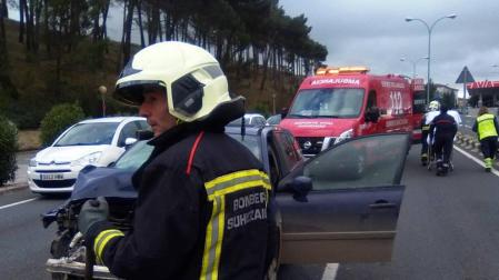 Los bomberos limpian la calzada tras el accidente.