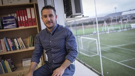 Ángel Alcalde, sentado en el ventanal de su despacho desde el que se puede observar uno de los campos de las instalaciones de Osasuna.