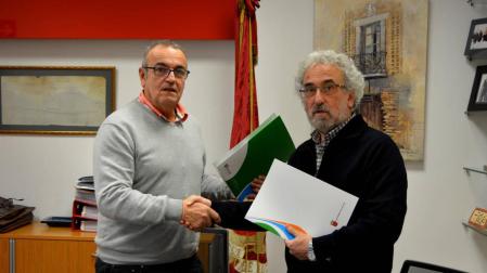 Valentín García (izda.) y Francisco Soto se dan la mano tras haber firmado el convenio.