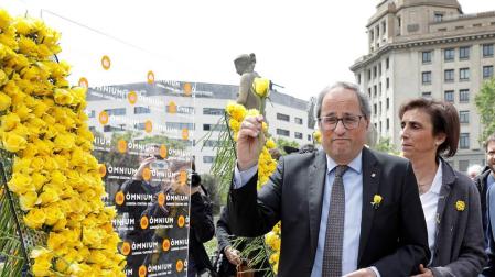 El presidente de la Generalitat, Quim Torra, coloca una rosa amarilla en el mural que recuerda a los independentistas presos instalado por Ómnium Cultural con motivo de la Diada de Sant Jordi.