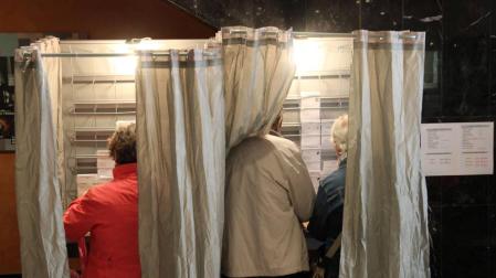 Dos personas preparan sus votos en una cabina durante las elecciones del 28A