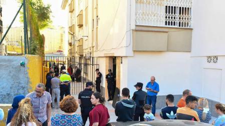 Vecinos de la barriada de Los Rosales y agentes de la Policía Nacional, a las afueras de la vivienda en la que ha tenido lugar el suceso.