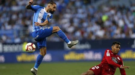 El defensa del Málaga Miguel Ángel Cifuentes chuta el balón ante el delantero argentino del Deportivo de La Coruña Matías Nahuel.