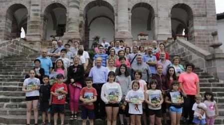 Los visitantes a la presentación de Conocer Navarra y los interventores posan con la revista frente a la iglesia de Ziga.