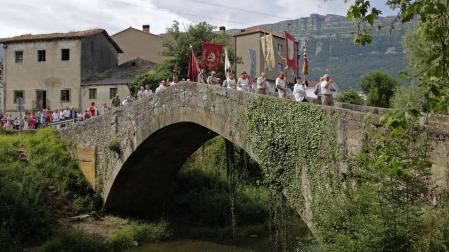 Vecinos de Uharte Arakil desfilan con la Virgen del Rosario por el puente medieval que salva el río Arakil.