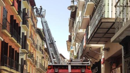 Los bomberos, durante la retirada del alero en mal estado en la calle San Antón.