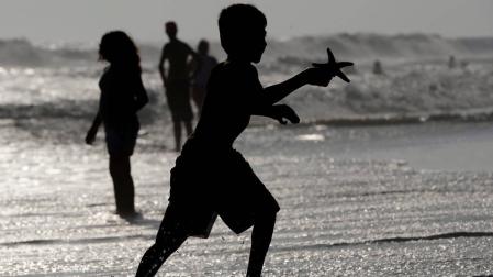 Varias personas se bañan en la playa de Huntington en California, Estados Unidos.