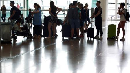 Varias personas esperan en el aeropuerto del Prat, Barcelona.