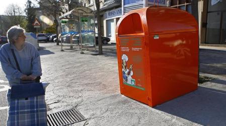 Una vecina de Pamplona pasea junto a un contenedor de reciclaje de aceite.
