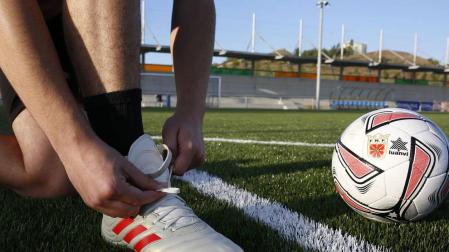 Un jugador juvenil del Burladés se ata las botas para empezar el entrenamiento.