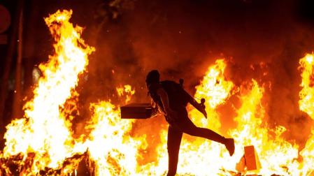 Un manifestante echa al fuego un cartón junto a la Delegación del Gobierno en Barcelona.