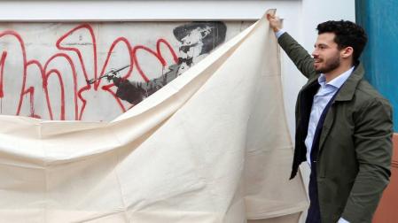 Varias fotografías retratan a un Banksy sin rostro trabajando en sus murales