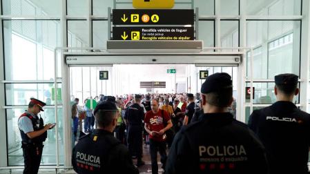 Agentes de los Mossos d'Esquadra y de la Policía Nacional controlan el acceso de personas a la terminal 1 del Aeropuerto de El Prat.