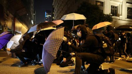 Manifestantes hongkoneses se protegen con paraguas de los gases lacrimógenos.