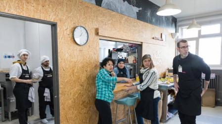 Varios voluntarios del comedor social Villa Javier Tudela se disponen a servir los platos a los usuarios.