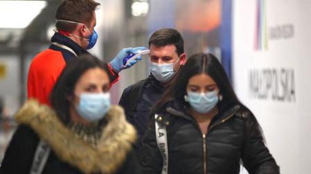 Un sanitario toma la temperatura a un joven en el aeropuerto de Cracovia.