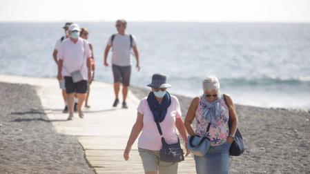 Varios turistas pasean este viernes por las inmediaciones del hotel en el que desde el pasado lunes permanecen incomunicados sus huéspedes y trabajadores al dar positivo en coronavirus cuatro de los que se alojaban en el centro turístico de Adeje, en el sur de Tenerife.