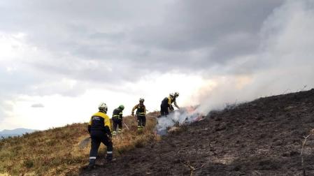 Bomberos trabajan en una quema de pastos de montaña.