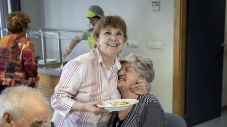 Gesto cariñoso entre dos de las usuarias del comedor del centro de mayores Oskia, en el barrio de San Juan.