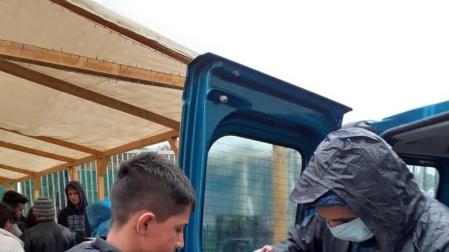 Un voluntario entrega una ración de comida a un niño refugiado e junto al campo de Moria.