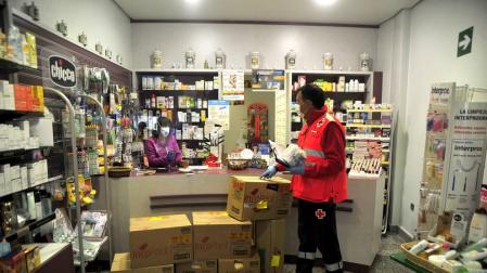 Pedro Arzoz recoge lo medicamentos que repartirá Cruz Roja en una farmacia de Tafalla.