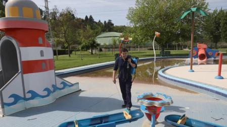 Un operario de mantenimiento del club deportivo Amaya, limpiando la zona de las piscinas infantiles.