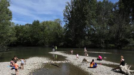 Disfrutar del sol e incluso refrescarse a la orilla del río Arga alivió del calor a decenas de personas.