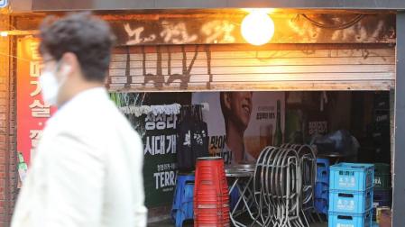 Un hombre pasa por delante de un bar cerrado en Seúl.