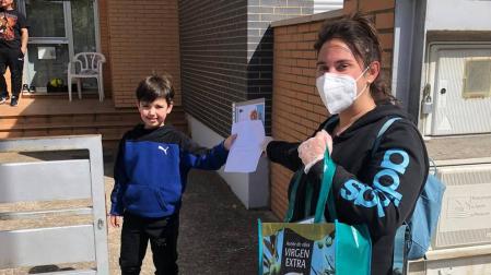 Una voluntaria entrega el diploma y mascarillas a un niño.
