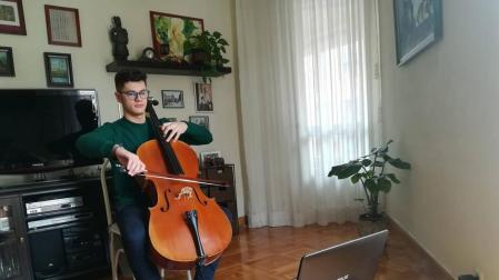 El pamplonés Fermín García Menéndez, de 19 años, tocando el violonchelo frente a la pantalla de su ordenador portátil.